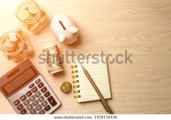 Piggy bank, calculator, dollar bill, glass jar\
filled with coins, notebook and pen, depict budget planning for\
basic needs, family, personal expense, Business and personal\
financial concept.