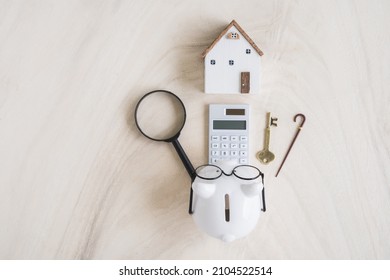 Piggy bank and calculator and home model and walking cane and magnifying glass and key put on the white desk in the office, Saving money for retirement and planning in the future concept.