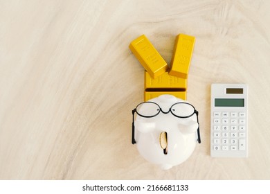 Piggy Bank And Calculator And Stack Gold Bar Put On The Wood In The Office, Saving Money And Loan For Business Investment Concept.