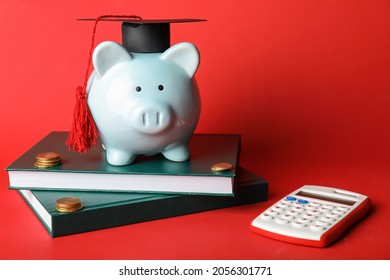 Piggy bank with graduation hat, books, calculator and coins on color background - Powered by Shutterstock