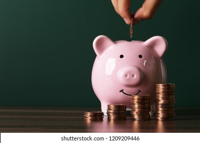 Piggy bank with growth coins against blank dark green chalkboard.