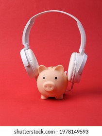 piggy bank with headphones on red background. 