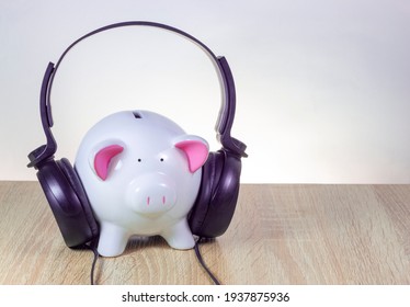 piggy bank with headphones on standing on a wooden table, white background