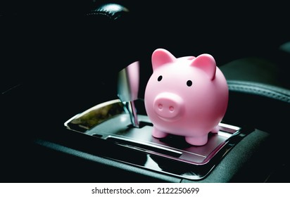 A Piggy Bank Inside A Car Next To The Automatic Transmission. Savings Concepts For Car Expenses, Car Insurance And Fuel Saving.
