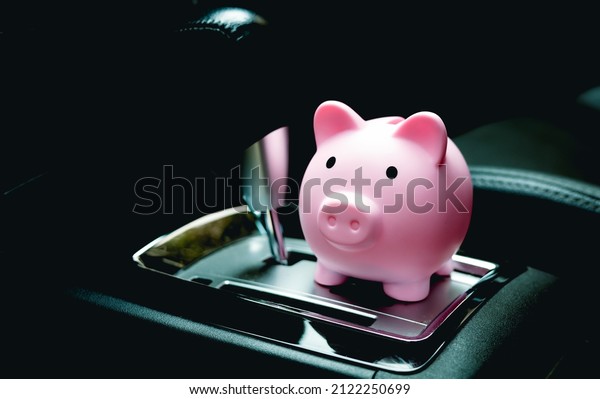 A piggy bank inside a car next to the automatic\
transmission. Savings concepts for car expenses, car insurance and\
fuel saving.\
