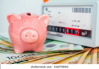 Piggy Bank Near A Natural Gas Meter At Home. The Symbolic Image Of The High Cost Of Natural Gas For Heating Homes In The Winter Time, Energy Efficiency. 