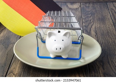 Piggy Bank On Plate Under Shop Basket And Germany Flag. Trade Inflation Concept