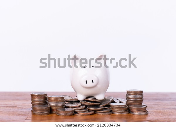 A\
piggy bank is placed on a pile of coins, Saving money for the\
happiness of life and goals in life. Money coins stack for growing\
growth with piggy bank, Saving investment with\
target.