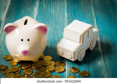 A Piggy Bank Put On The Stacking Gold Coins And Car Model On The Vintage Blue Background, Saving Money For Buying Or Loan For Planned Investment In The Future Concept.