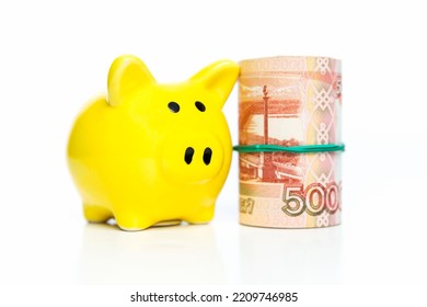 Piggy Bank And A Roll Of Money Worth 5,000 Rubles. Finance And Savings. White Background. Close-up.
