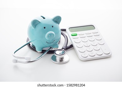 Piggy bank with stethoscope and calculator on white background, health insurance concept