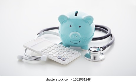 Piggy bank with stethoscope and calculator on white table, health saving account, tax, hsa concept