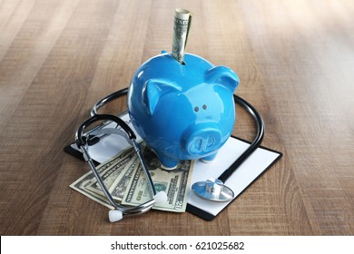 Piggy bank with stethoscope and clipboard on table