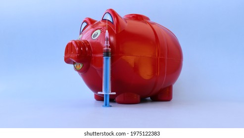 Piggy Bank With Syringe Lying Straight Over Blue Background.