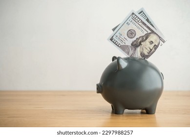 Piggy bank and US dollar banknotes on wooden table with white wall background copy space. Personal finance, money savings management for education, retirement, investment, travel, etc concept. - Shutterstock ID 2297988257