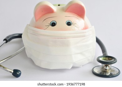 Piggy bank wearing a surgical mask and a stethoscope on a white background.