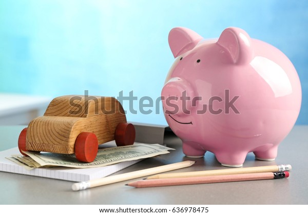 Piggy bank and wooden\
toy car on table
