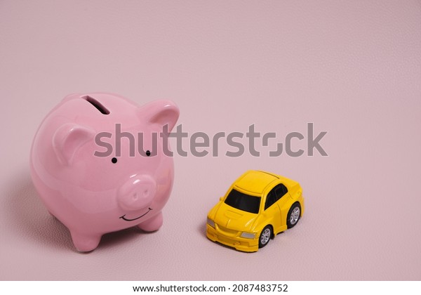 Piggy bank and\
yellow car on pink\
background