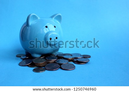 piggy blue piggy standing on a pile of money coins
