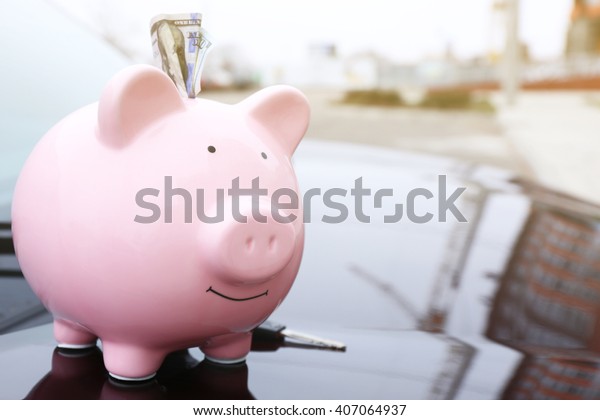 Piggy money box with cash and key on car bonnet at\
the street