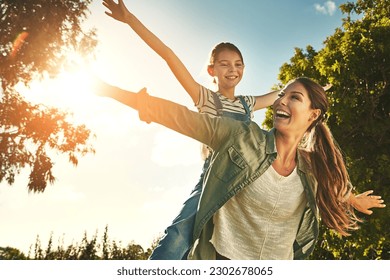 Piggyback, flying and a mother and child in nature for bonding, happiness and love in summer. Laughing, smile and a mom and a girl kid in a park or garden for playing together and quality time - Powered by Shutterstock