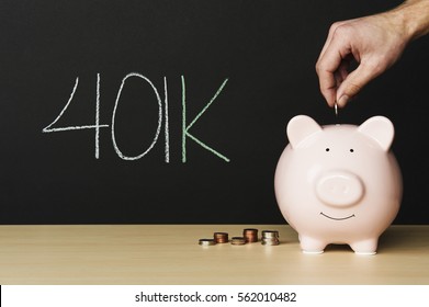 Piggybank with 401k written on a blackboard in the background. Money beside the piggybank with a hand putting a coin in.