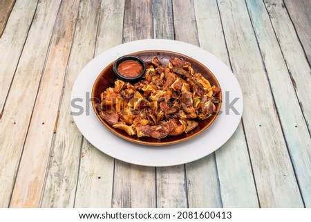 Pig's ear with spicy sauce on a white plate is a kind of ration served in Spanish bars that consists of grilled pig's ear