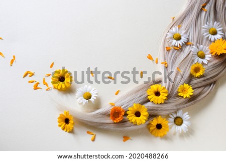 Pigtail. Chamomile and calendula flowers in blond hair.