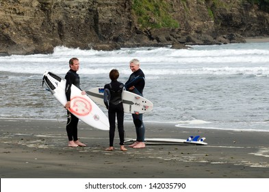 PIHA, NZ - JUNE 01 2013: Gropup of wave surfers talking on Piha beach near Auckland.According to the International Surfing Association the estimate number of surfers worldwide is 23 million.