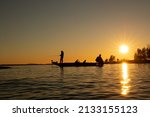 Pike fishing in the sunset with high speed bass boat. Lake Vänern in  Sweden. Angler casting with fishing rod, warm and orange glowing sky.