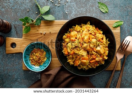 Pilaf or pilau with chicken, traditional uzbek hot dish of boiled rice, chicken meat, vegetables and spices on plate, top view.
