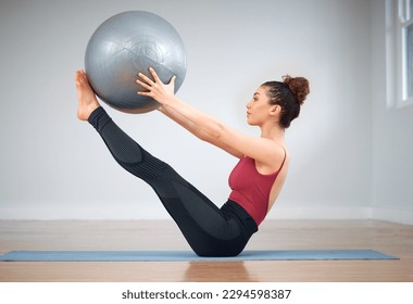 Pilates can be challenging. Shot of a young woman doing core exercises using a medicine ball. - Shutterstock ID 2294598387