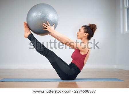 Pilates can be challenging. Shot of a young woman doing core exercises using a medicine ball.