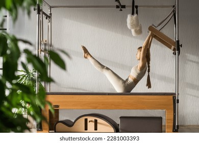 Pilates fitness trainer doing exercises on in pilates studio. Balanced Body Cadillac machine for fitness workouts in gym. Fit, healthy and strong authentical body. Fitness concept.