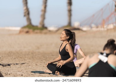 A Pilates instructor leads a group in a focused breathing exercise on the beach, enhancing mindfulness and relaxation - Powered by Shutterstock