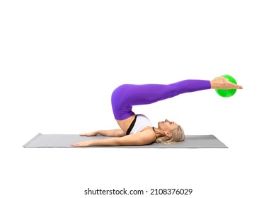 Pilates, inverted poses. Athletic beautiful woman in sportswear practice roll over exercise with a small fit ball between her feet, isolated on white.