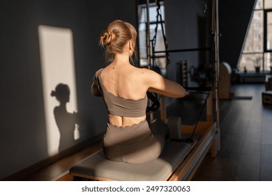 Pilates reformer and Balanced Body Ladder Barrel equipment in a contemporary fitness studio with natural light from large windows. - Powered by Shutterstock