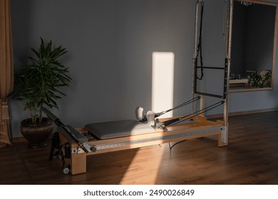 Pilates reformer equipment in a contemporary fitness studio with natural light from large windows. - Powered by Shutterstock