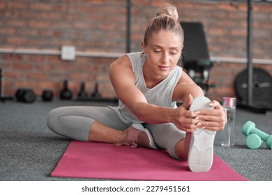 Pilates, stretching leg and woman in gym getting ready to start workout, training or exercise. Sports, fitness or female athlete stretch, warm up or prepare for exercising for flexibility on yoga mat
