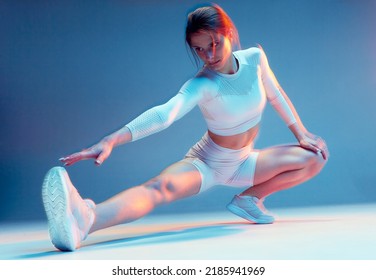 Pilates workout. Fit sports girl stretching legs, hips muscles, squatting. Fitness training, wellness. Long exposure - Powered by Shutterstock