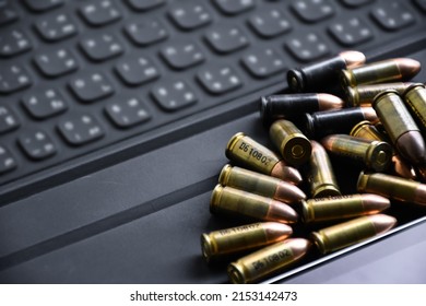 Pile of 9mm pistol bullets on taplet keyboard and screen, soft and selective focus, concept for learning types of bullets by using smart devices to search and store the database.
