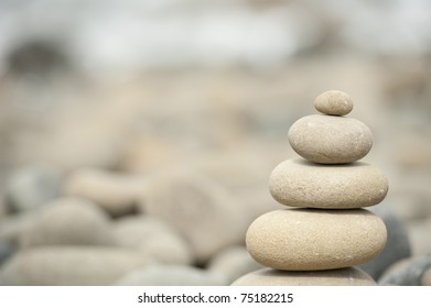pile of balanced stones on rocky beach with ocean in background