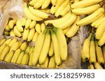 Pile of bananas in multiple bunches inside cartons. Large fruit shipment for transport and sale at a market. Fresh bananas on display in a grocery store or fruit shop.