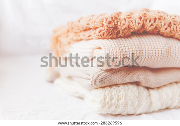 白い背景にベージュ毛の服の山 温かい編み物のセーターとスカーフを一つの山に積み重ねる Instagramの調子の模倣 の写真素材 今すぐ編集