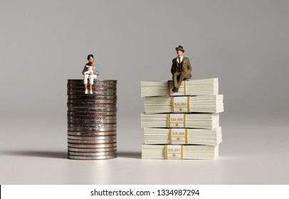 A pile of bills and coins. Miniature people. The concept of wage inequalities according to women's career break.