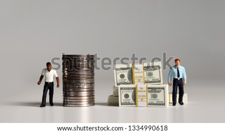 A pile of bills and coins. Miniature people. The concept of racial and income disparity.