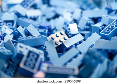 Pile of blue color building blocks with selective focus and highlight on one particular block using available light.