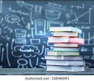 A pile of books with mathematical equations and graphs in the screen against a dark background - Powered by Shutterstock