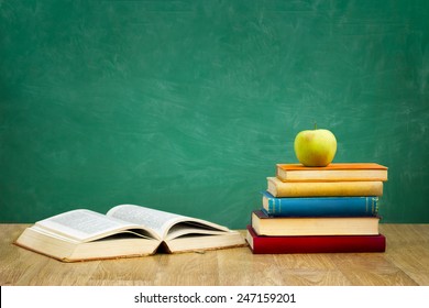 Pile Of Books With One Book Open On Empty Green  School Board Background