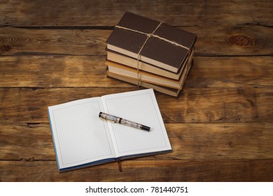 A pile of books tied with a rope, a diary, a pen on a wooden background. beautiful perspective.